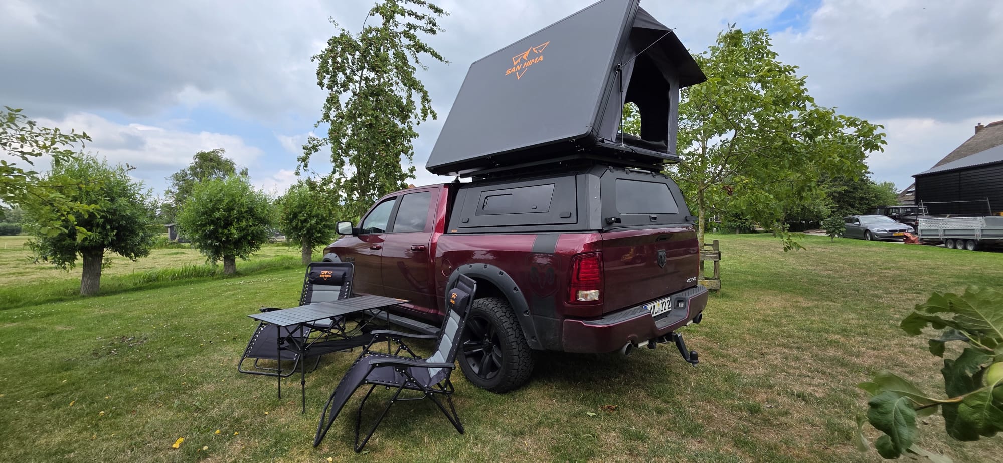RAM pick-up met LCM Oasis daktent, SAN HIMA campingstoelen en campingtafel op het gras